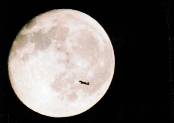 月球的照片，喷气式飞机在它前面飞行
