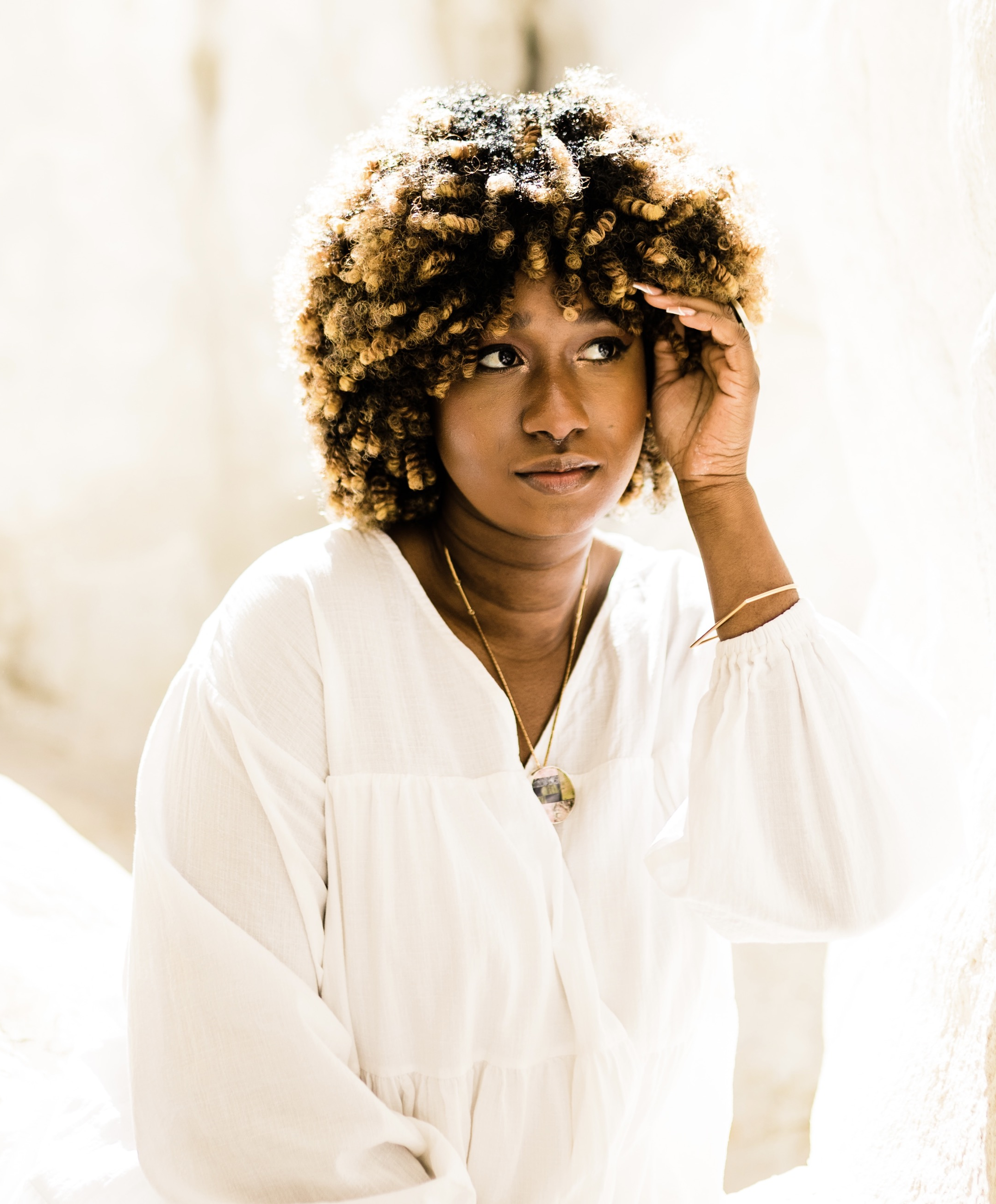Irina Amouzou, a black femme person,  in a white shirt with a bright background